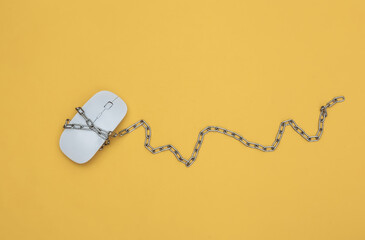Pc mouse wrapped in steel chain on yellow background. Top view
