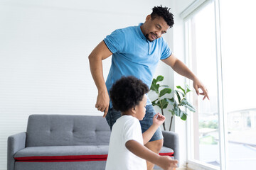 African American father dancing and playing with cute curly little son in room at home. Happy African family spending time together on holiday at home. family, kid and holiday concept