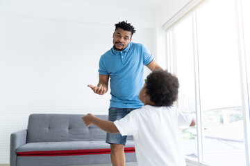 African American father dancing and playing with cute curly little son in room at home. Happy African family spending time together on holiday at home. family, kid and holiday concept