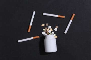Smoking cure. Bottle of pills and cigarettes on a black background. Quitting smoking