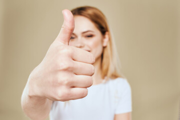 Cheerful woman in a white T-shirt gestures with her hands emotions beige background