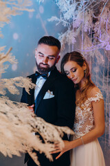 Portrait of the bride and groom. Beautiful decorations. Blue background.
