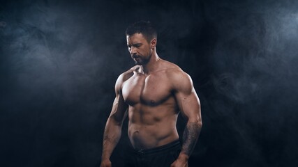 Naklejka na ściany i meble Fit and sporty bodybuilder over black background. Sportsman in studio. Sport and fitness concepts.