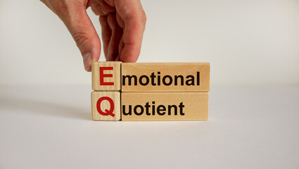 Wooden cubes and blocks with words 'EQ - emotional quotient'. Male hand. Psychological concept. Copy space, beautiful white background.