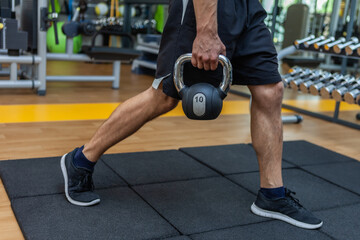 Fitness man exercising with a kettlebell in modern gym.