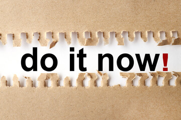 DO IT NOW, text on white paper on torn paper background