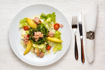 Classic Nicoise Salad On a white plate, on a white wooden table