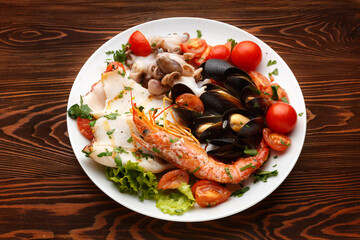 Assorted seafood on a plate on a dark wooden table.