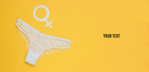 Women's sexy lace panties and gender Femen symbol on yellow background with space for your text. The concept of feminism. Top view