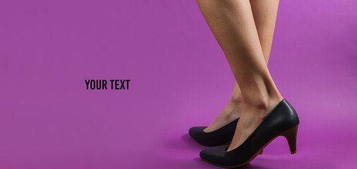 Slim female legs with classic high heel shoes on purple background with copy space. Studio fashion...