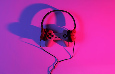 Wired headphones with gamepad. Neon blue-red gradient light. Retro wave, 80s pop culture. Top view