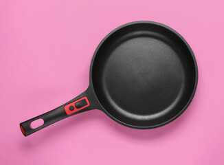Frying pan with a non-stick coating on pink background. Сooking equipment. Top view