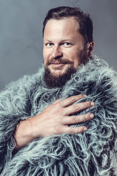 Solid bearded man in a fur mantle studio portrait