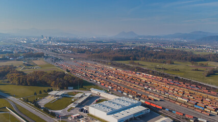 Aerial photo of a train marshalling yard on a warm day in autumn. Visible a large amount of train tracks and freight cars.