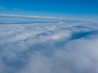 Fototapeta premium Aerial view. Flying over white clouds during the day in sunny weather.