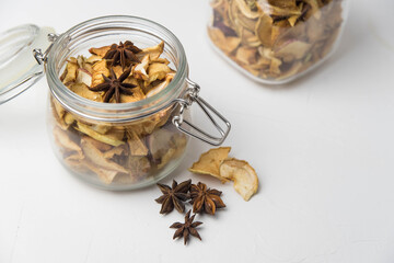 Homemade crispy sun dried organic apple slices. Close up of apple chips with spice in glass jar isolated on white background with copy space for text