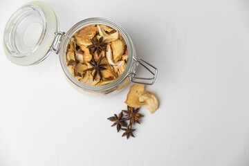 Homemade crispy sun dried organic apple slices. Close up of apple chips with spice in glass jar isolated on white background with copy space for text