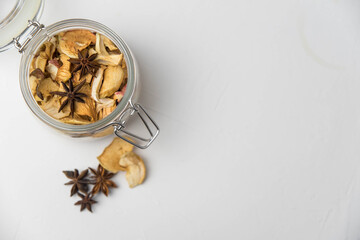 Homemade crispy sun dried organic apple slices. Close up of apple chips with spice in glass jar isolated on white background with copy space for text