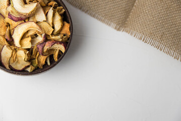 Homemade crispy sun dried organic apple slices. Close up of apple chips with spice in bowl isolated on white background with copy space for text