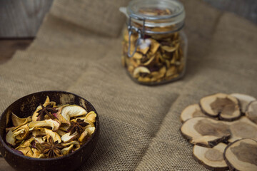 Homemade crispy sun dried organic apple slices. Close up of apple chips with spice in bowl on brown wooden background with copy space for text