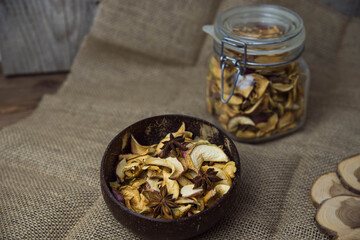 Homemade crispy sun dried organic apple slices. Close up of apple chips with spice in bowl on brown wooden background with copy space for text