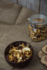 Homemade crispy sun dried organic apple slices. Close up of apple chips with spice in bowl on brown wooden background with copy space for text
