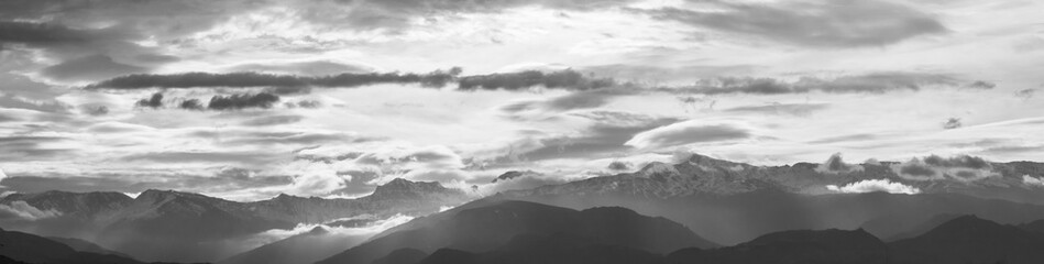 Obraz premium Panoramic view of Sierra Nevada between clouds (some of them lenticular) and sunbeams at sunrise