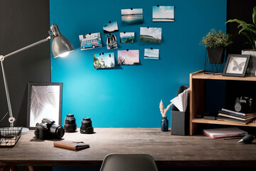 Workplace of contemporary photographer with photos of nature on blue board