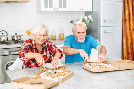 Senior Couple Eating Pizza In The Kitchen