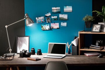 Workplace of photographer with photos of nature on blue board in front of table