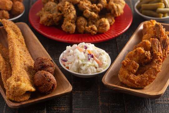 Breaded And Fried Fillets Of Fish With Hushpuppies On A Wooden Table