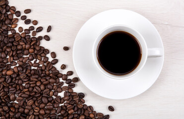 cup of coffee on a grey wooden background and roasted coffee bea