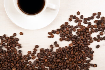 cup of coffee on a grey wooden background and roasted coffee bea