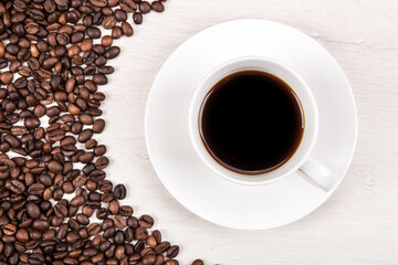 cup of coffee on a grey wooden background and roasted coffee bea