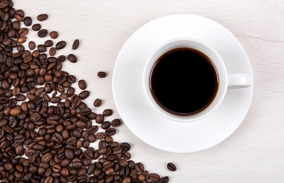cup of coffee on a grey wooden background and roasted coffee bea