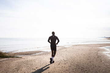 African boy who goes running on the beach against the light. Concept of sport and health.