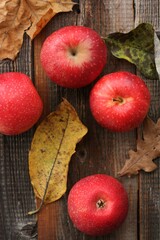 Juicy red apples and autumn leaves on the table