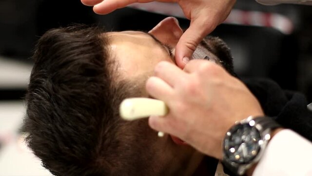 Close up Barber shaves beard using shaving foam