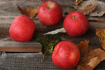 Juicy red apples and autumn leaves on the table