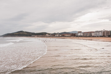 Surfers in waves. Surfers and waves crashing on beach. Swimmers in water on aerial seascape background. Active lifestyle. Extreme sport. Beautiful seascape with cliff and surfers. Vastness concept.