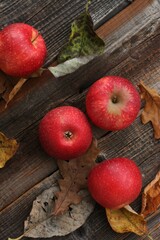 Juicy red apples and autumn leaves on the table