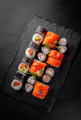 set of sushi roll with salmon, avocado, cream cheese, cucumber, rice, tuna in plate on black background