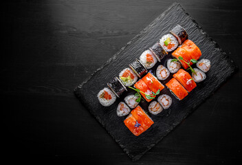 set of sushi roll with salmon, avocado, cream cheese, cucumber, rice, tuna in plate on black background © pavel siamionov