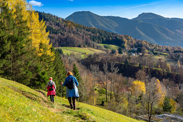 Fototapeta na wymiar Herbst in Bayern: Zwei Seniorinnen wandern den Tegernseer Höhenweg mit Blick auf den Wallberg
