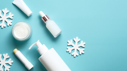 Winter cosmetic products set with snowflakes on pastel blue background. Skin care concept. Flat lay, top view.