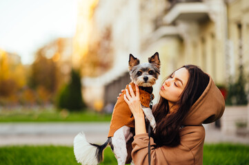 Close-up photo, a woman holding a biewer terrier dog and looking away. Walk with pet concept. Close-up photo, a woman holding a biewer terrier dog and looking away. Walk with pet concept. Background