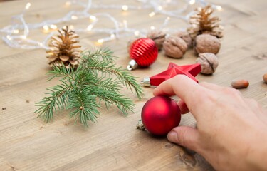 Hand holds red Christmas ball against wooden background. Beautiful festive New Year's toys. New Year's holidays. Christmas Holidays.