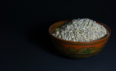 Uncooked pearl barley in a ceramic bowl with folk patterns