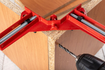 Chipboard in an angular carpentry clamp. Drilling in a furniture board.