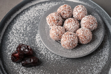 Vegan date candy on a gray plate next to the dates on a concrete tray